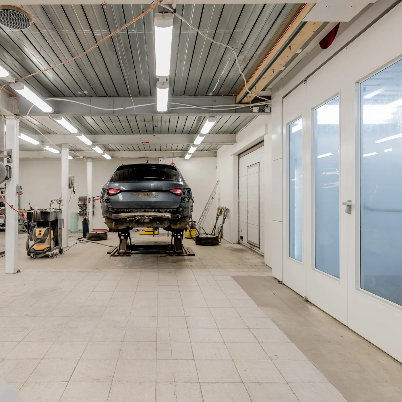 Helle Werkstatthalle, ein Auto steht auf der Hebebühne